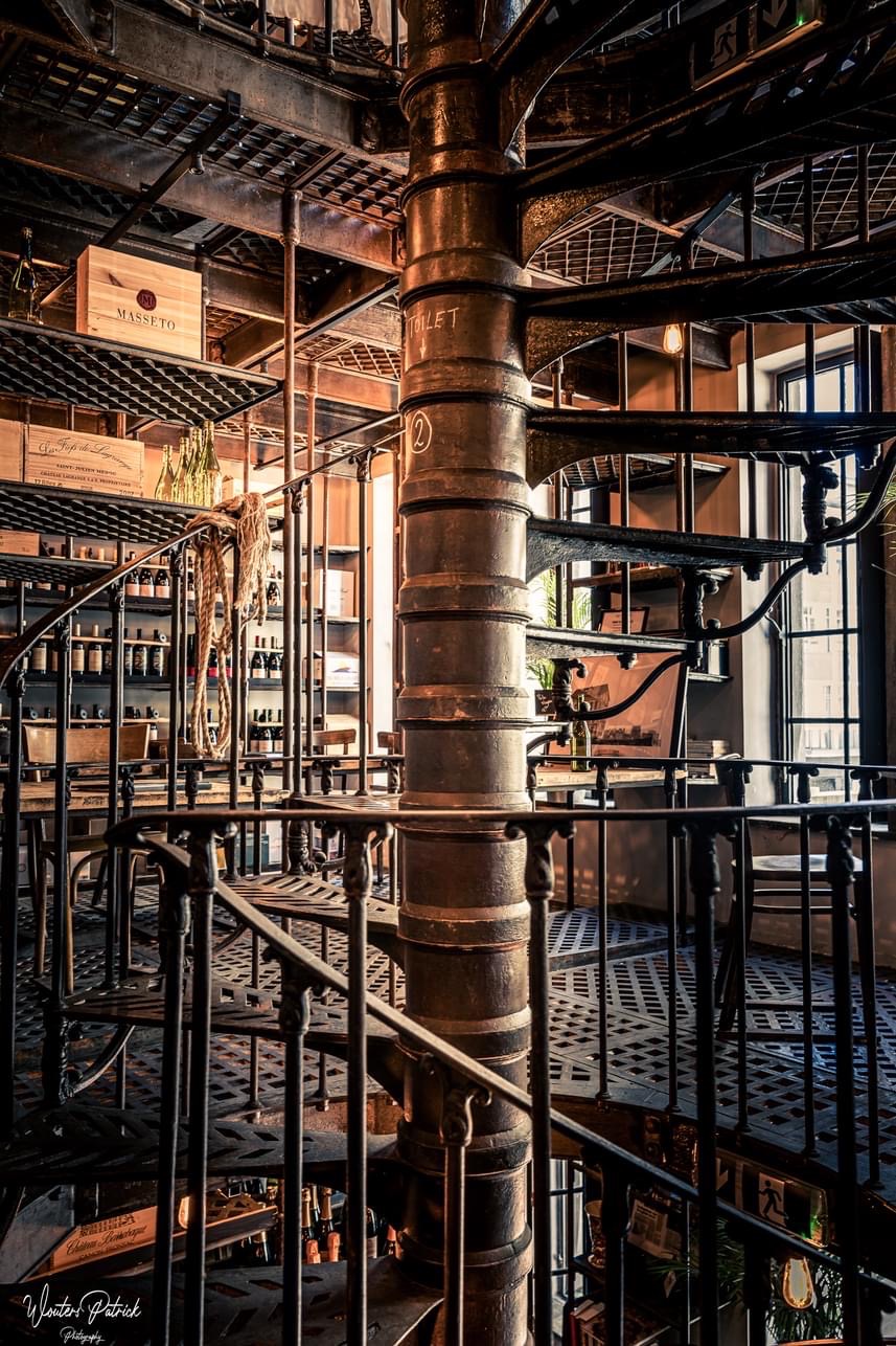 De monumentale gietijzeren wenteltrap en wijnrekken van Het Archief